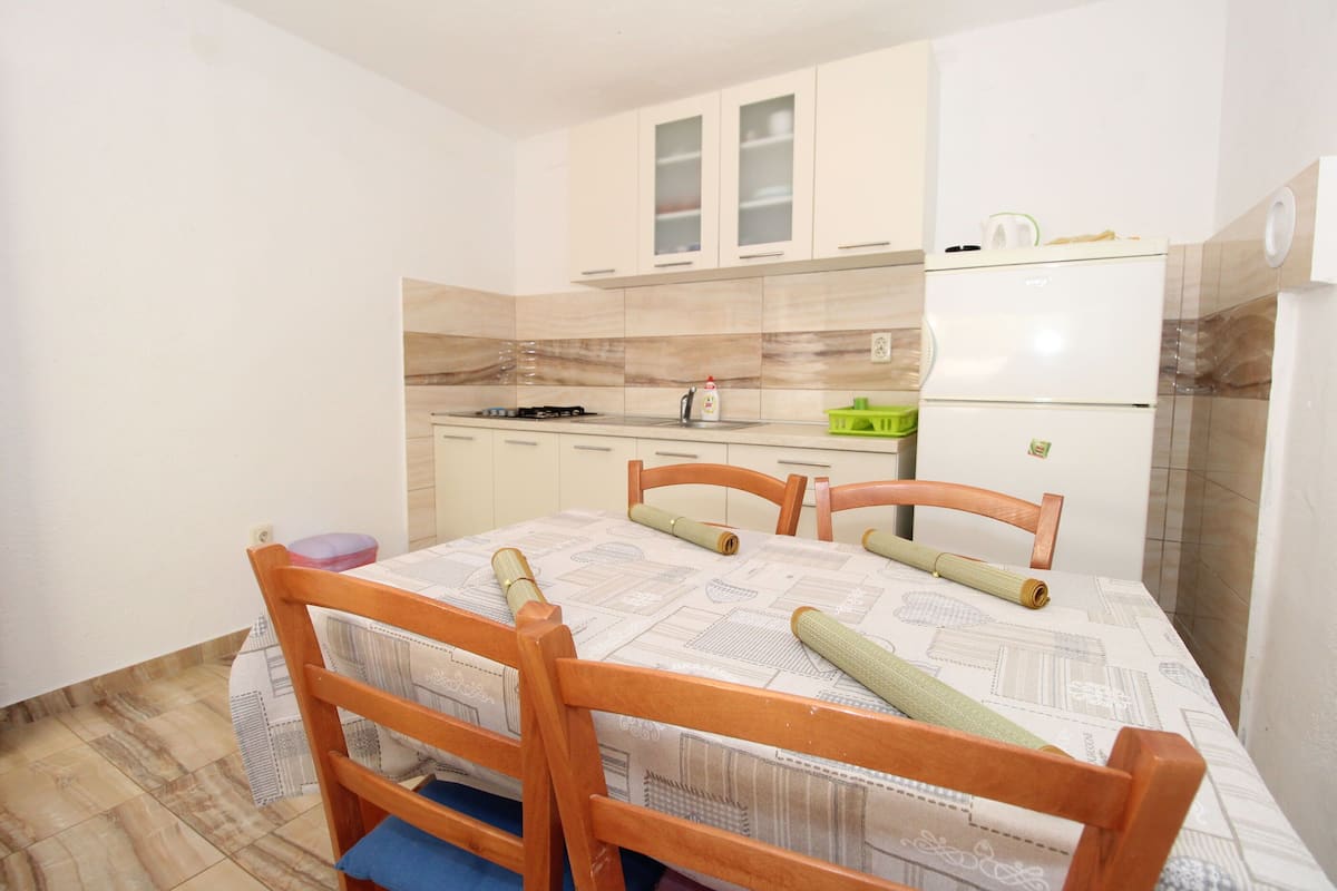 Une cuisine de taille réduite comprenant une table à manger, des chaises et un réfrigérateur.
