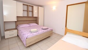 A bedroom with a bed, a wardrobe, a nightstand, and a wall-mounted light. - Apartment Marija (Kolan)