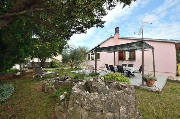 A pink house with a covered patio, stone wall, and outdoor seating area. - House Marlu (Marcana)
