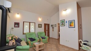 A living room with two green armchairs, a small table with a vase, and a white chair. - House Marlu (Rakalj)