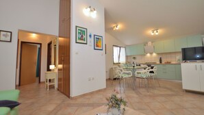 A modern kitchen with white cabinets, a dining area with a table and chairs, and a living room with a sofa and a coffee table. - House Marlu (Rakalj)