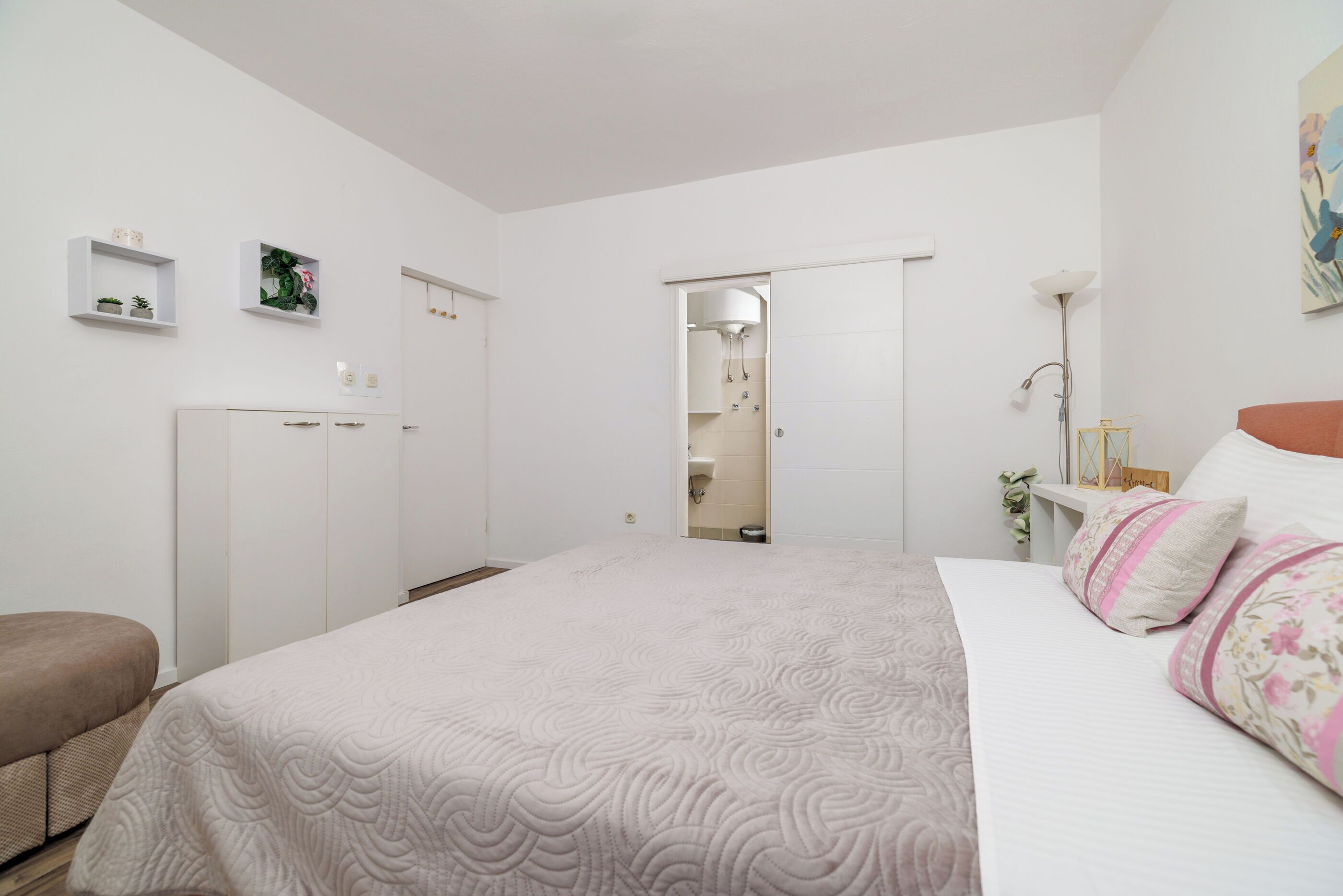Ein Schlafzimmer mit Bett, Kleiderschrank, Nachttisch und Spiegel.