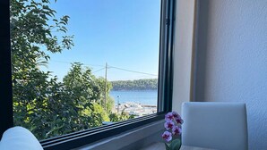 A room with a view of the sea through a large window, a table with a vase of flowers, and a chair. - Apartments Near the sea Barbat (Barbat)