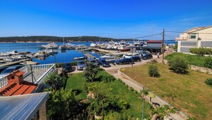 A marina with boats docked, a parking area, and a building with a red roof. - Apartments Near the sea Barbat (Barbat)