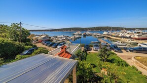A marina with boats docked, a parking area with cars, and a view of the water and distant land. - Apartments Near the sea Barbat (Barbat)