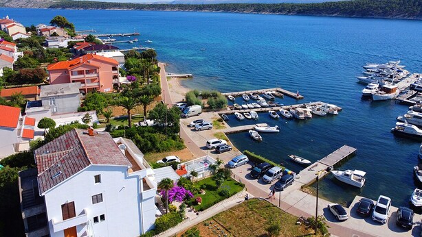 A coastal town with a marina, residential buildings, and a clear blue sea. - Apartments Near the sea Barbat (Barbat)