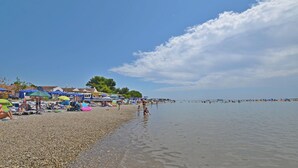 Une plage de galets avec des parasols et des gens.