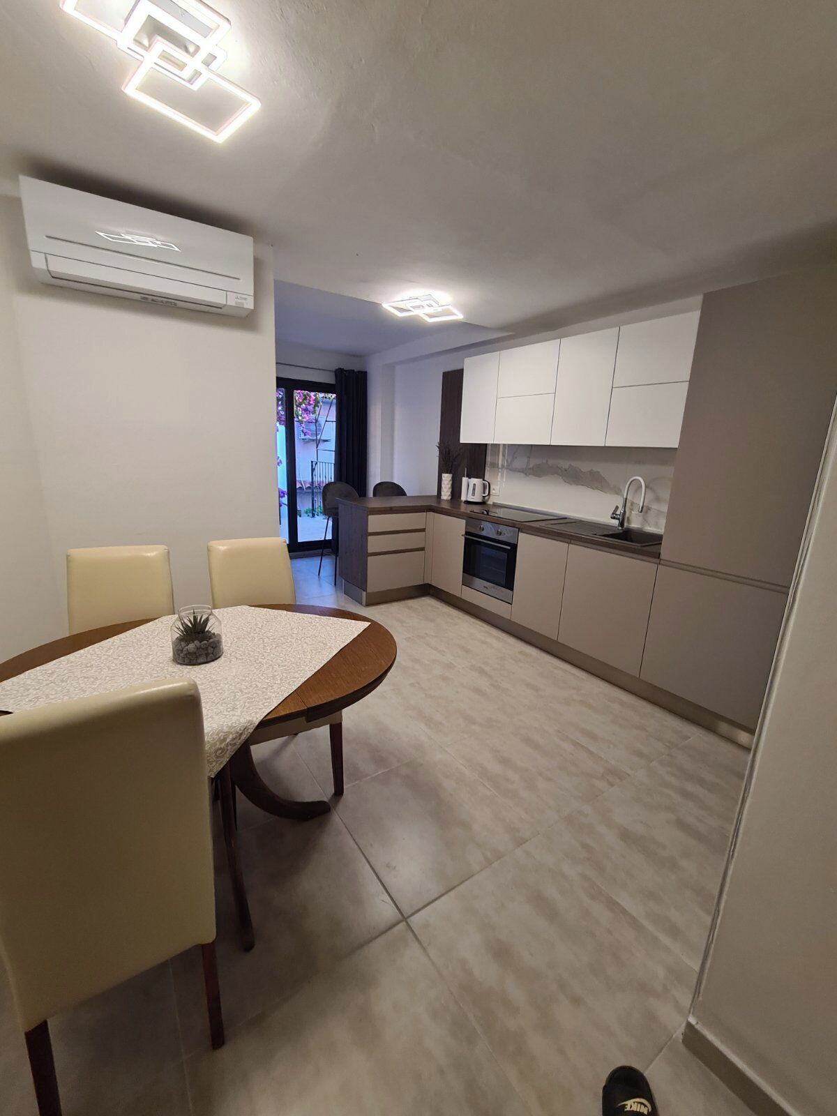 Una cocina moderna con armarios blancos, una mesa de comedor con sillas y un horno empotrado.