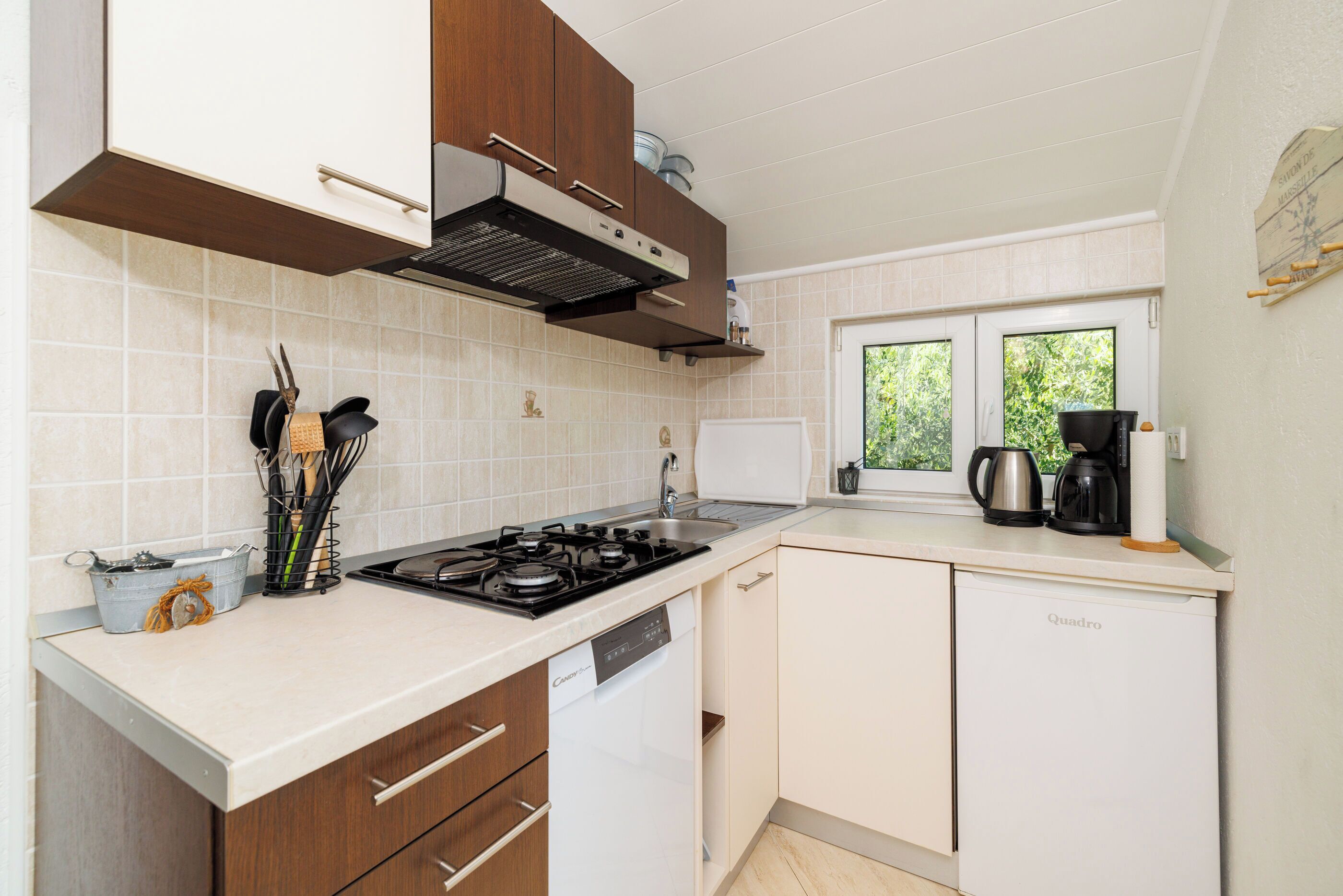 A compact kitchen with a dishwasher, stove, and a window providing natural light.