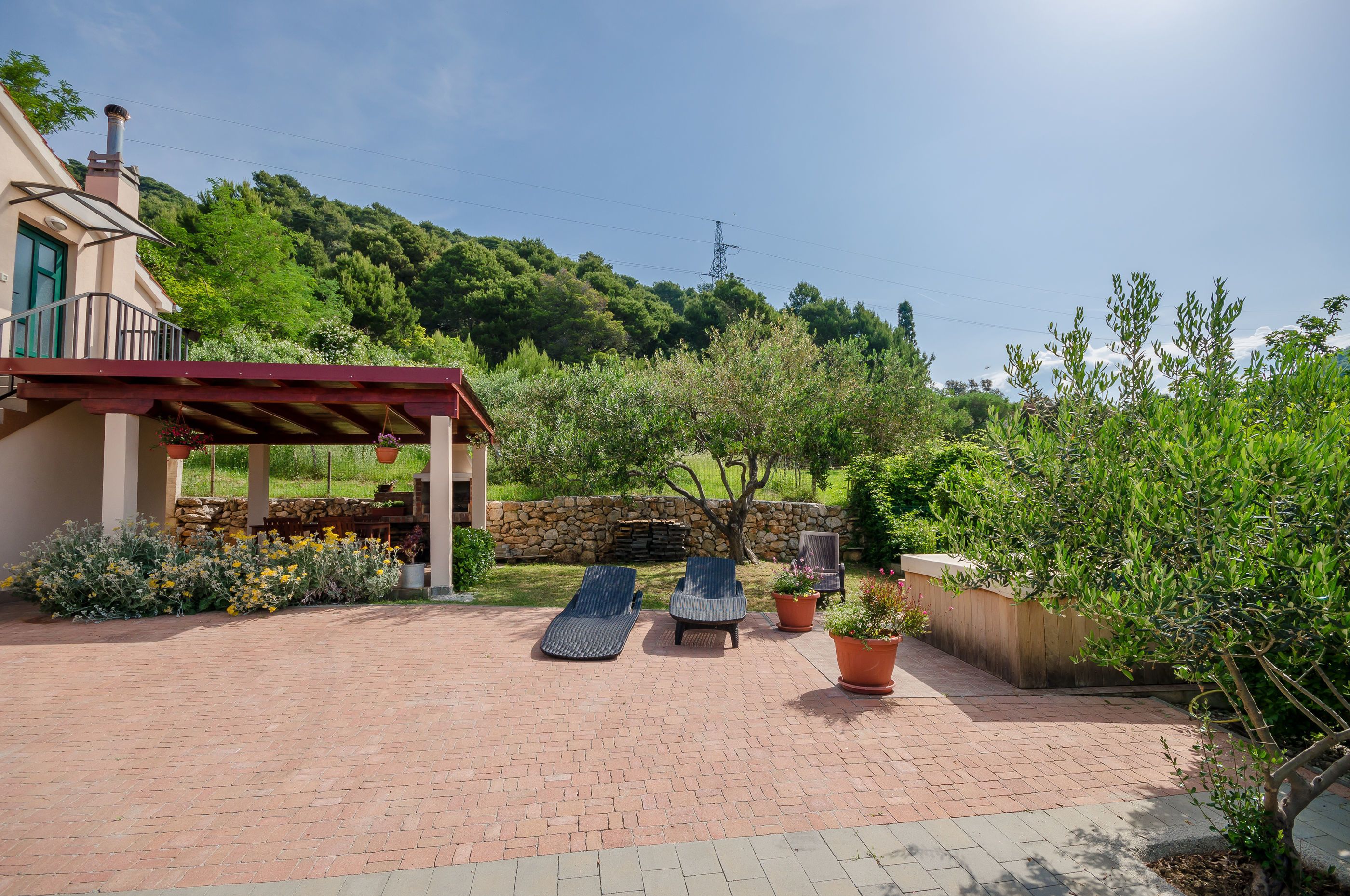 Eine Terrasse mit zwei Liegestühlen, einer Steinmauer und Kübelpflanzen.