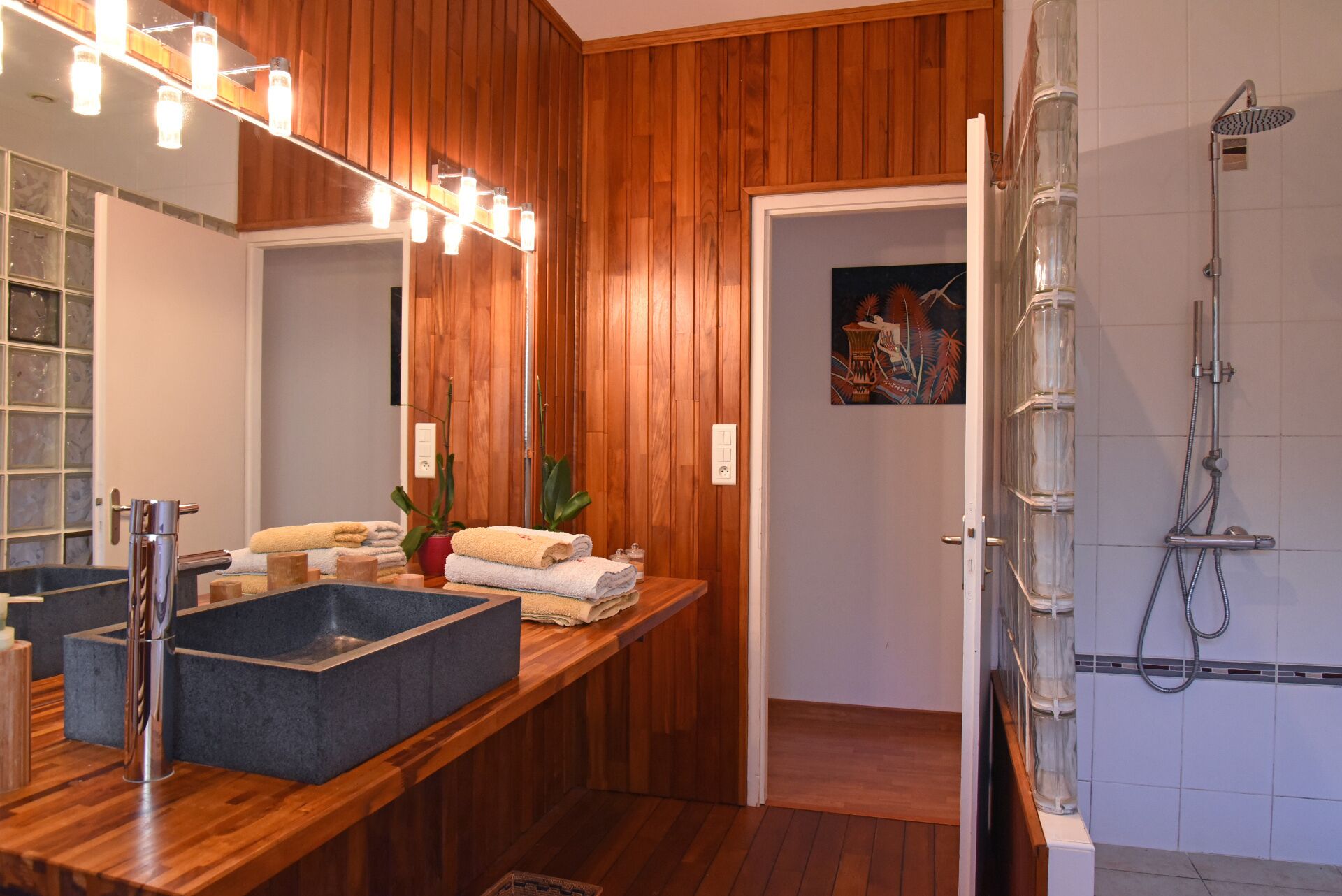 Een moderne badkamer met een houten wastafelmeubel, een grote spiegel en een douche met glazen wanden.