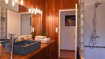 Een moderne badkamer met een houten wastafelmeubel, een grote spiegel en een douche met glazen wanden.
