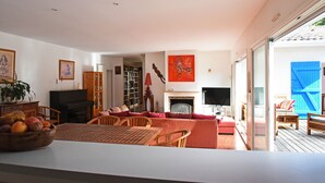 A spacious living room with a piano, bookshelves, a fireplace, and a large window. - exceptional, quiet, golf on 27 holes character villa, heated pool (Biscarrosse)