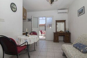 A compact living space with a dining table, a red chair, a sofa, and a wooden cabinet. - Apartments Tonin (Ivan Dolac)