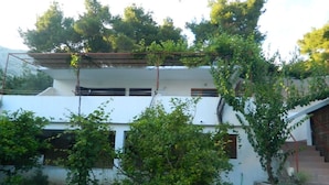 A two-story building with a stone wall in front, a staircase on the right, and greenery around. - Apartments Tonin (Ivan Dolac)