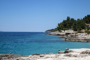 A coastal landscape with rocky terrain and clear blue sea. - Apartments Tonin (Ivan Dolac)