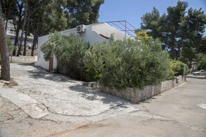 A residential building with a stone wall, a white exterior, and a red balcony. - Apartments Tonin (Ivan Dolac)