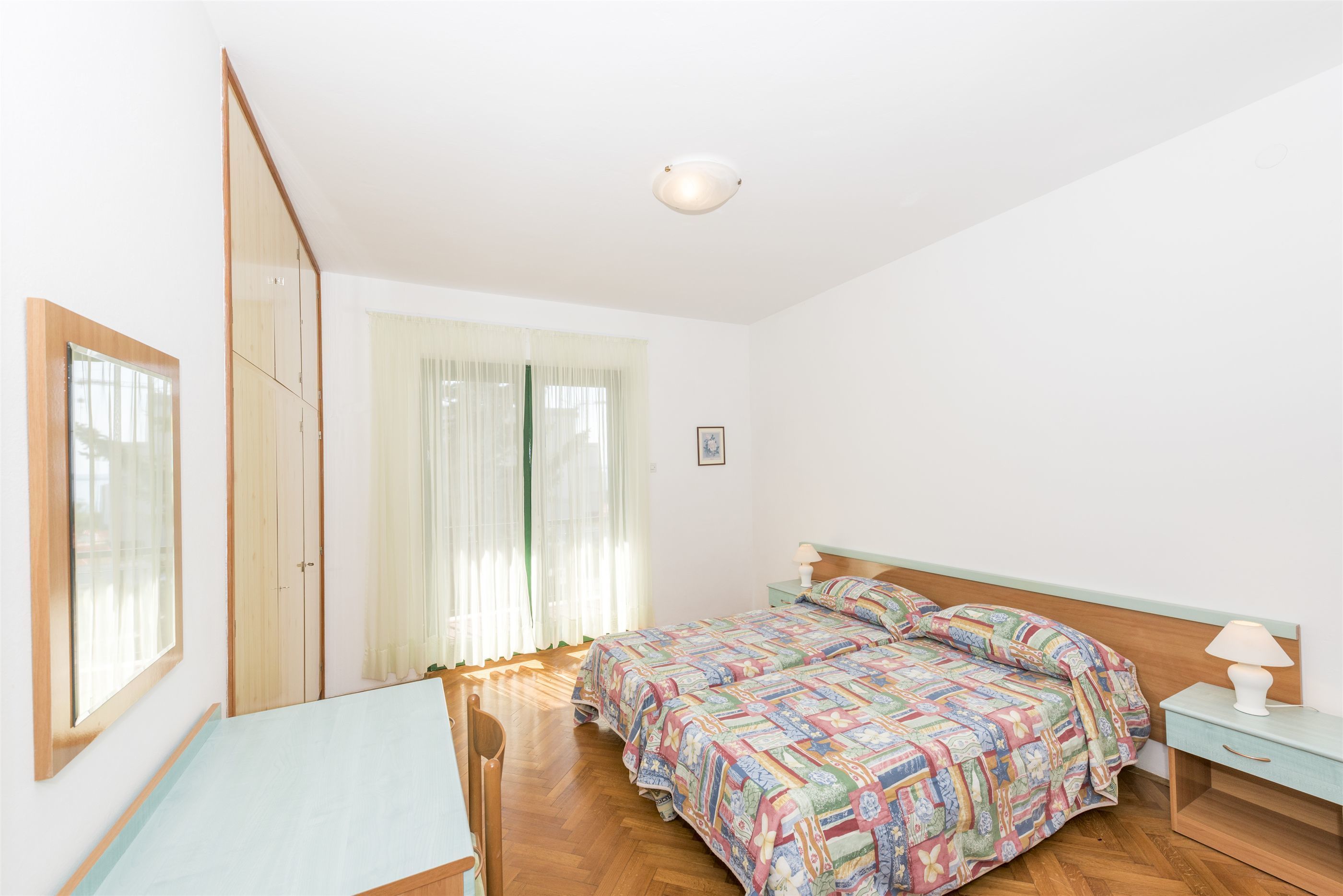 A bedroom with a bed, a desk, and a chair.