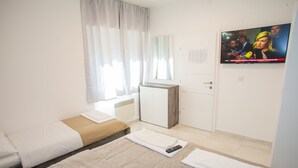 A hotel room with a bed, a desk, a TV, and a window with curtains. - Apartment Primorska (Novalja)