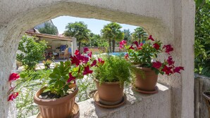 A stone archway with potted plants and flowers. - Apartments Vesna With Pool (Vodice)