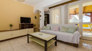 A living room with a sofa, television, and a coffee table. - Apartment Marija (Brodarica)