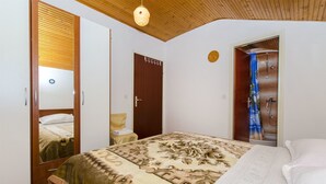 A bedroom with a bed, a wooden wardrobe, a door, and a shower area. - Apartment Marija (Brodarica)