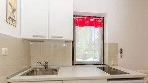 A modern kitchen with white cabinets, a stainless steel sink, and a dishwasher. - Apartments Pharos (Stari Grad)
