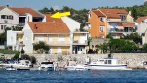 Una cittadina costiera con edifici lungo il lungomare, barche ormeggiate e cielo sereno.