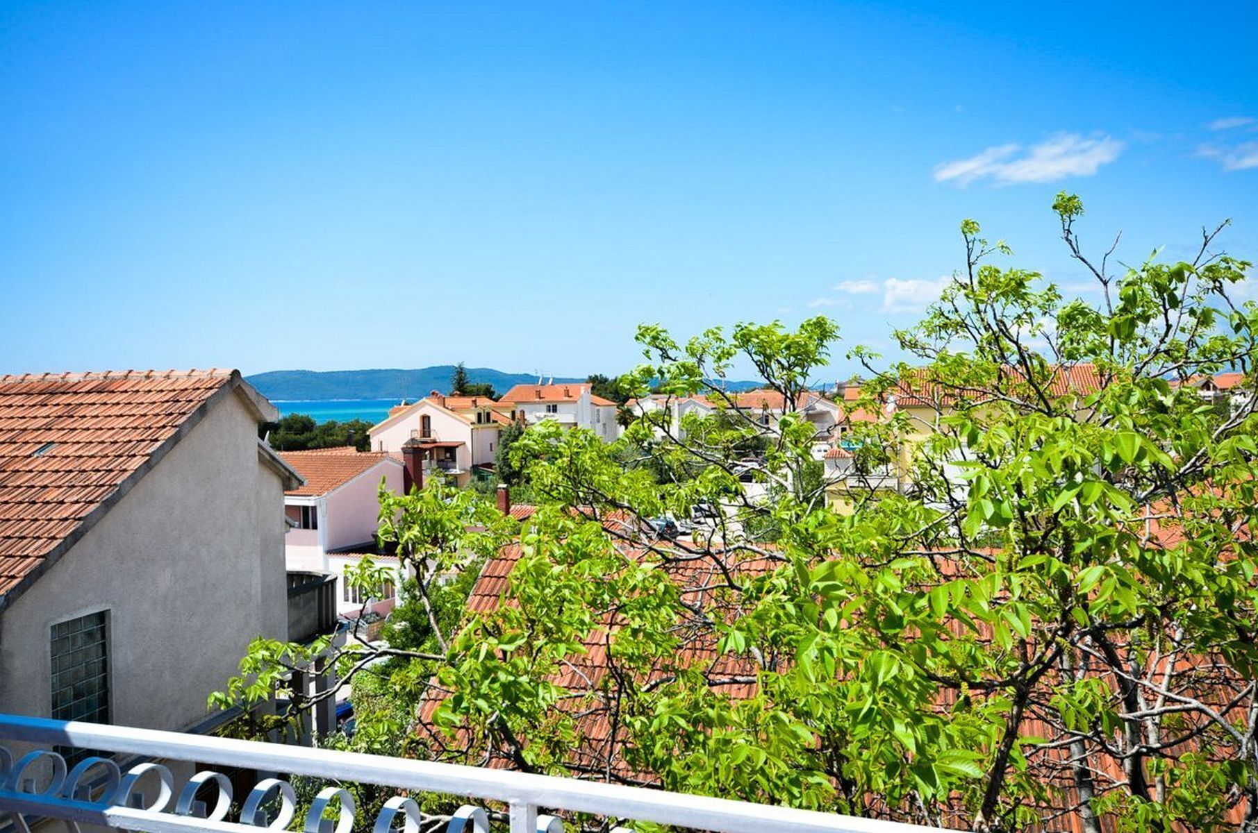 Un quartier résidentiel situé sur la côte, où les maisons se distinguent par leurs toits recouverts de tuiles rouges et où le ciel est d’un bleu éclatant.