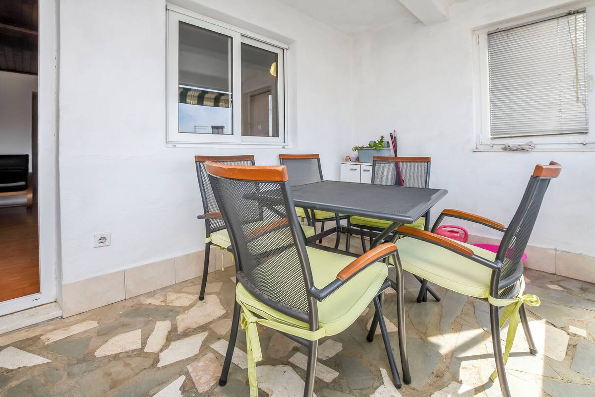 A dining area with a table and chairs, a window, and a small cabinet with items on it.