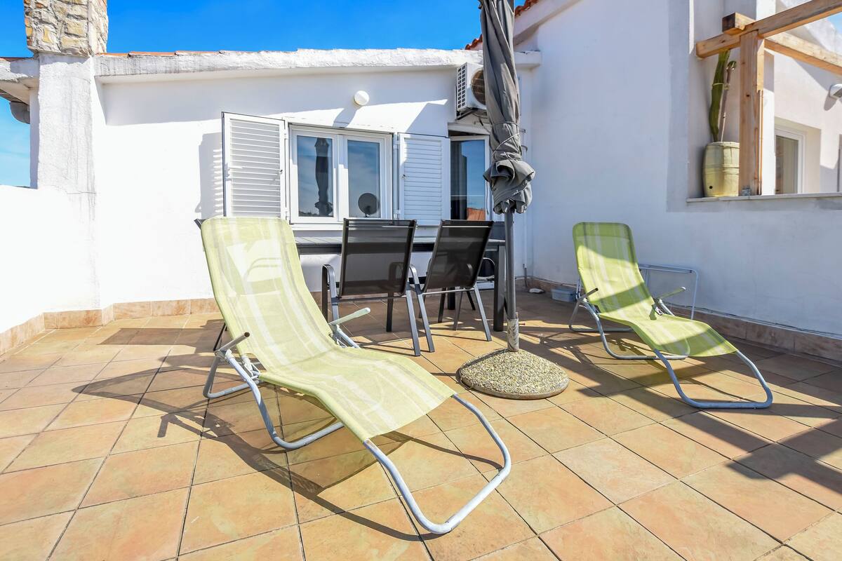 A terrace with two sun loungers, a table, and chairs.