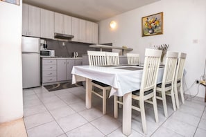 A compact kitchen with white cabinets, a microwave, and a stove. - Apartments Ercegovic (Rogoznica)