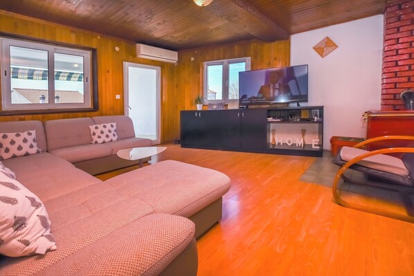 Un salon confortable avec un canapé, un téléviseur et un plancher en bois.