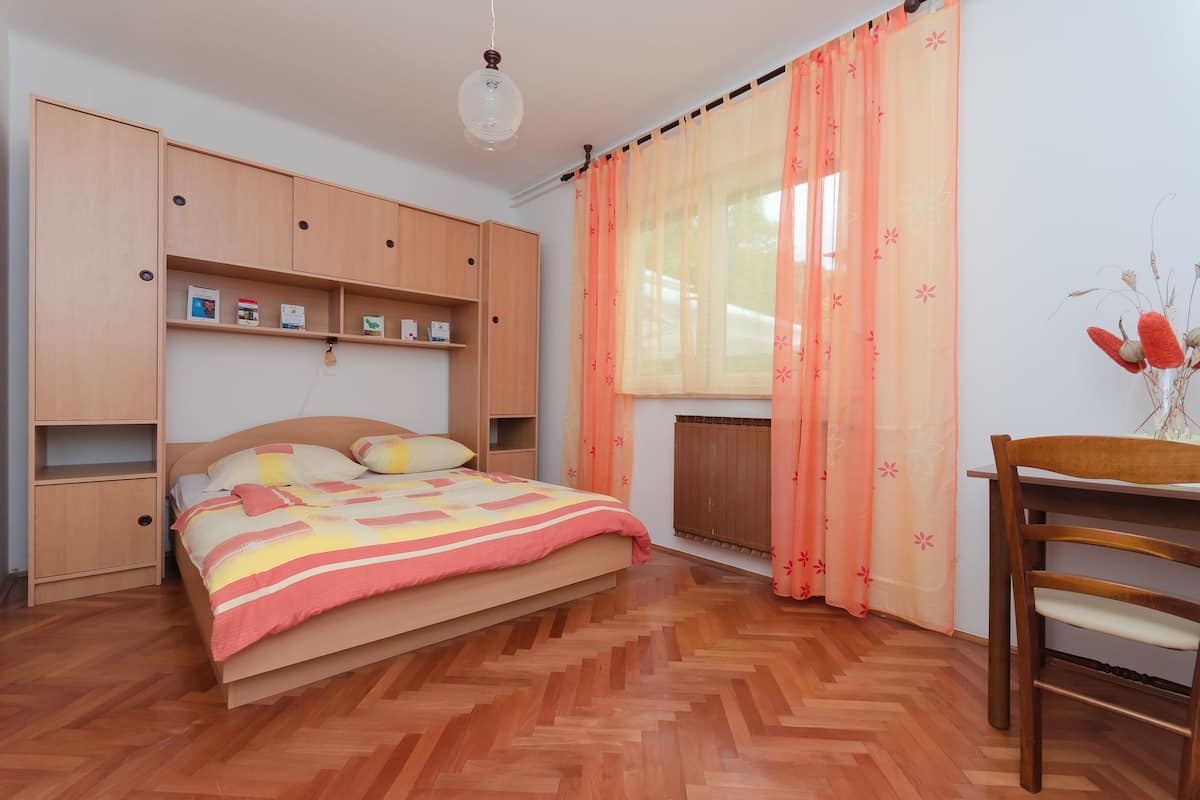Ein Schlafzimmer mit Bett, Holzschrank, Regalen und einem Stuhl.
