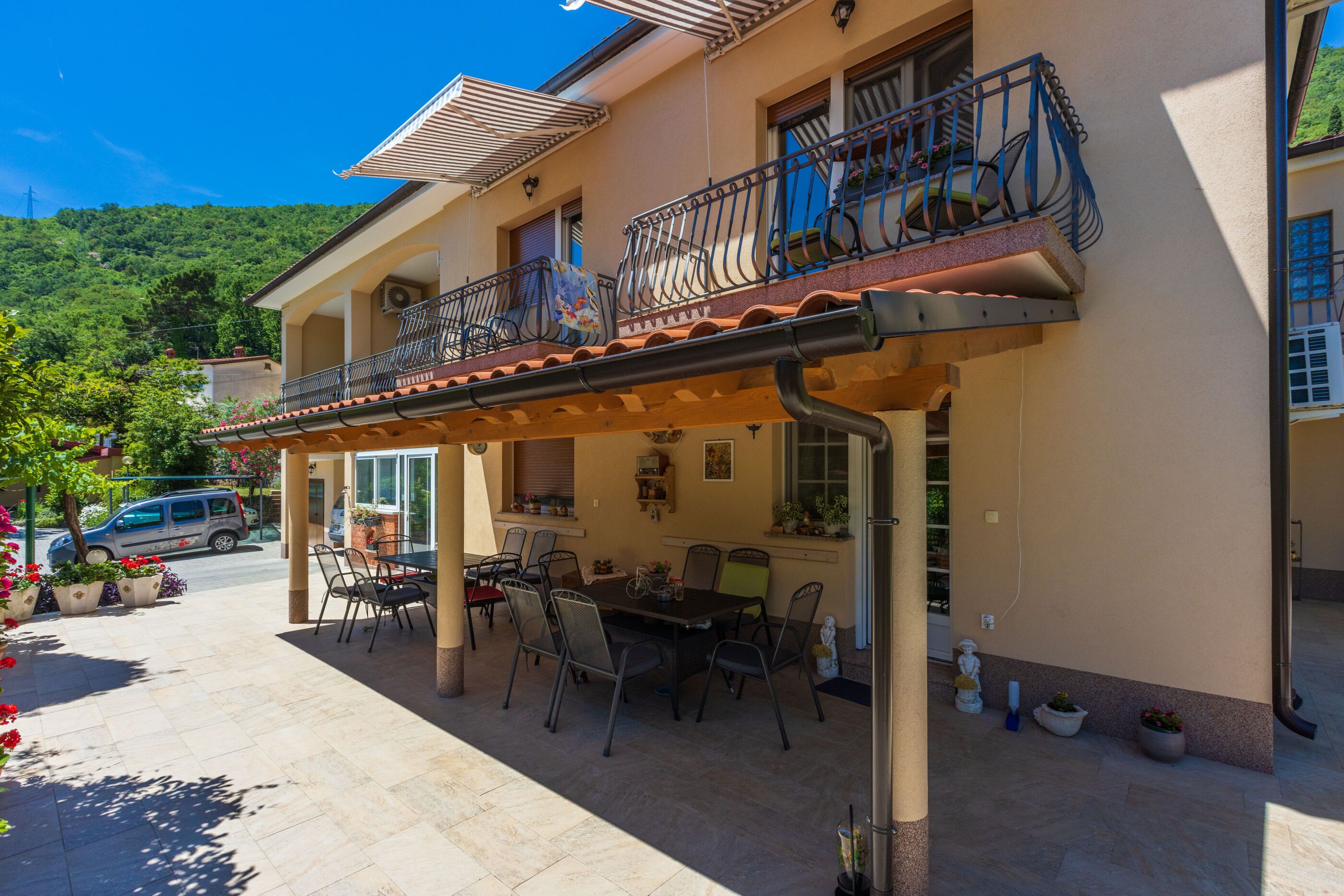 A two-story building with a balcony, outdoor seating area, and potted plants.