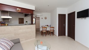 Ein modernes Wohnzimmer mit einem Glastisch, einer Couch und einem Essbereich mit Holzsesseln und einem Tisch.