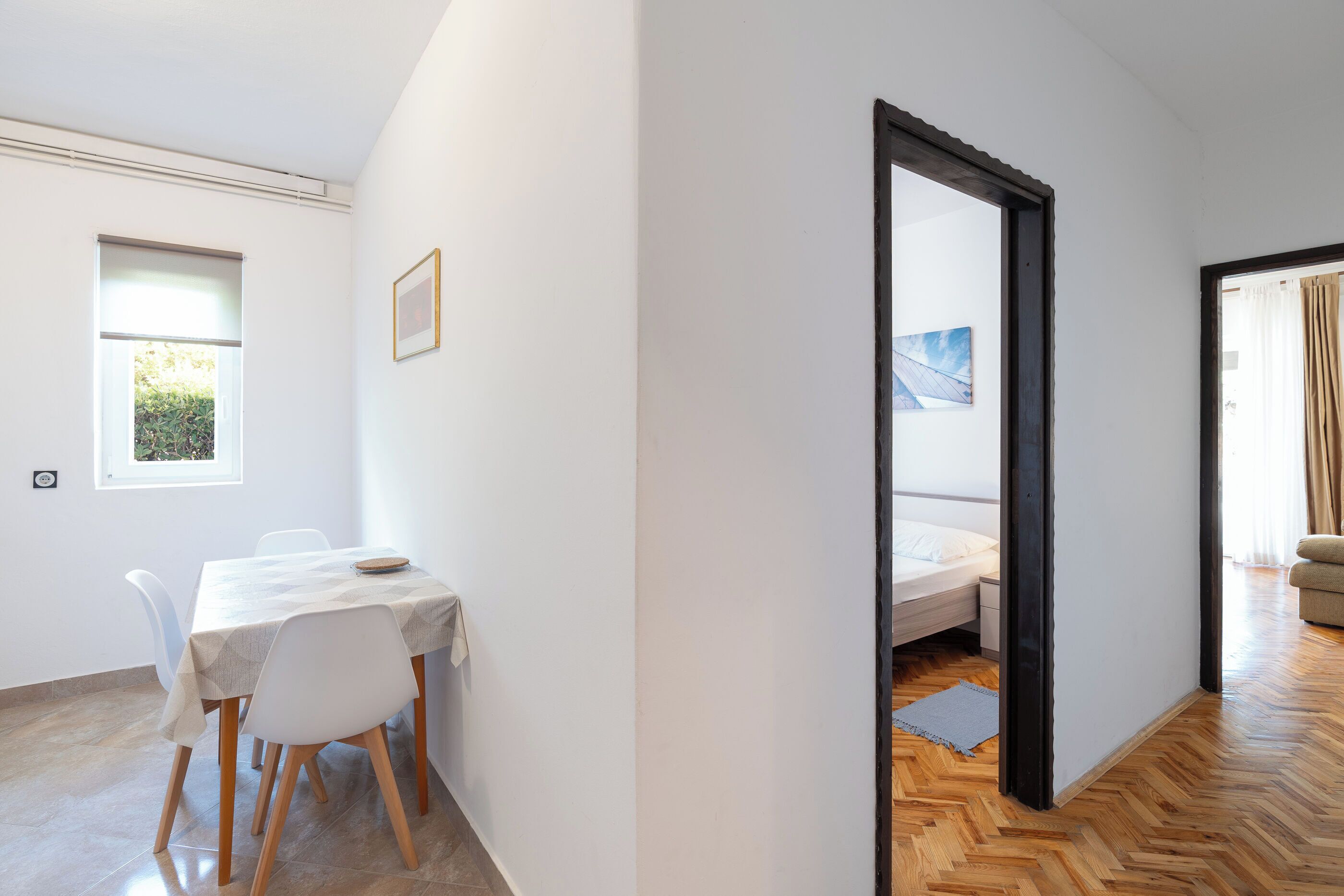 A room with a dining table, chairs, a bed, and a large mirror.