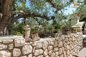 Un muro de piedra con una pequeña construcción de piedra y plantas en macetas.