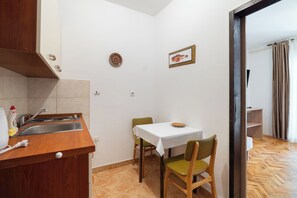 Una pequeña cocina con un fregadero, estufa y comedor con mesa y sillas.