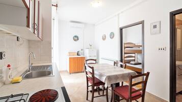 Una cocina compacta con estufa a gas, lavamanos y un comedor con mesa y sillas.