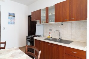 Una cocina con armarios de madera, una estufa, un fregadero y un calendario en la pared.