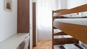 A bunk bed with a wooden headboard, a white bedside table, and a wardrobe. - Apartments Ivo (Pag)