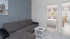 Ein modernes Wohnzimmer mit einem grauen Sofa, einem kleinen weißen Tisch und einem Bild eines Bootes an der Wand.