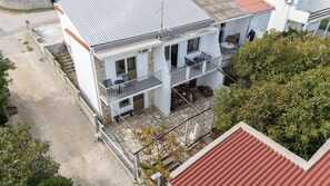 Ein zweistöckiges Gebäude mit Balkon, Terrasse und einem kleinen Garten.