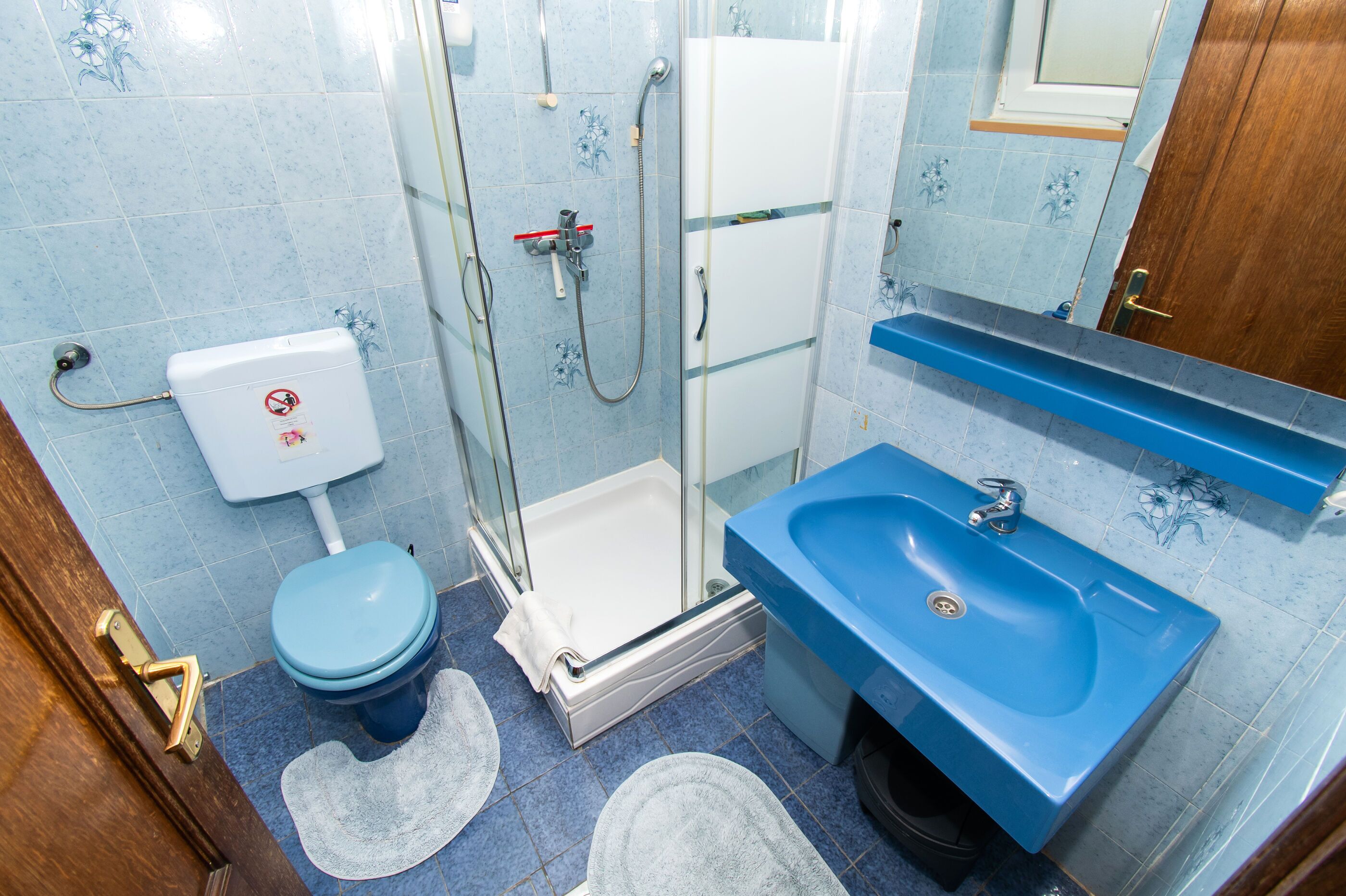 A bathroom with a blue sink, white toilet, and glass shower enclosure.