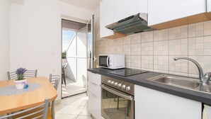 A modern kitchen with a microwave, oven, and sink. - Apartment Danijela (Bibinje)