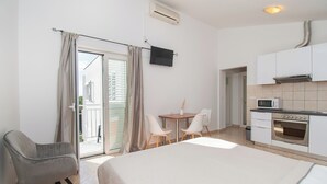 A hotel room with a bed, a desk, a chair, a kitchenette, and a sliding glass door to the balcony. - Apartment Danijela (Bibinje)