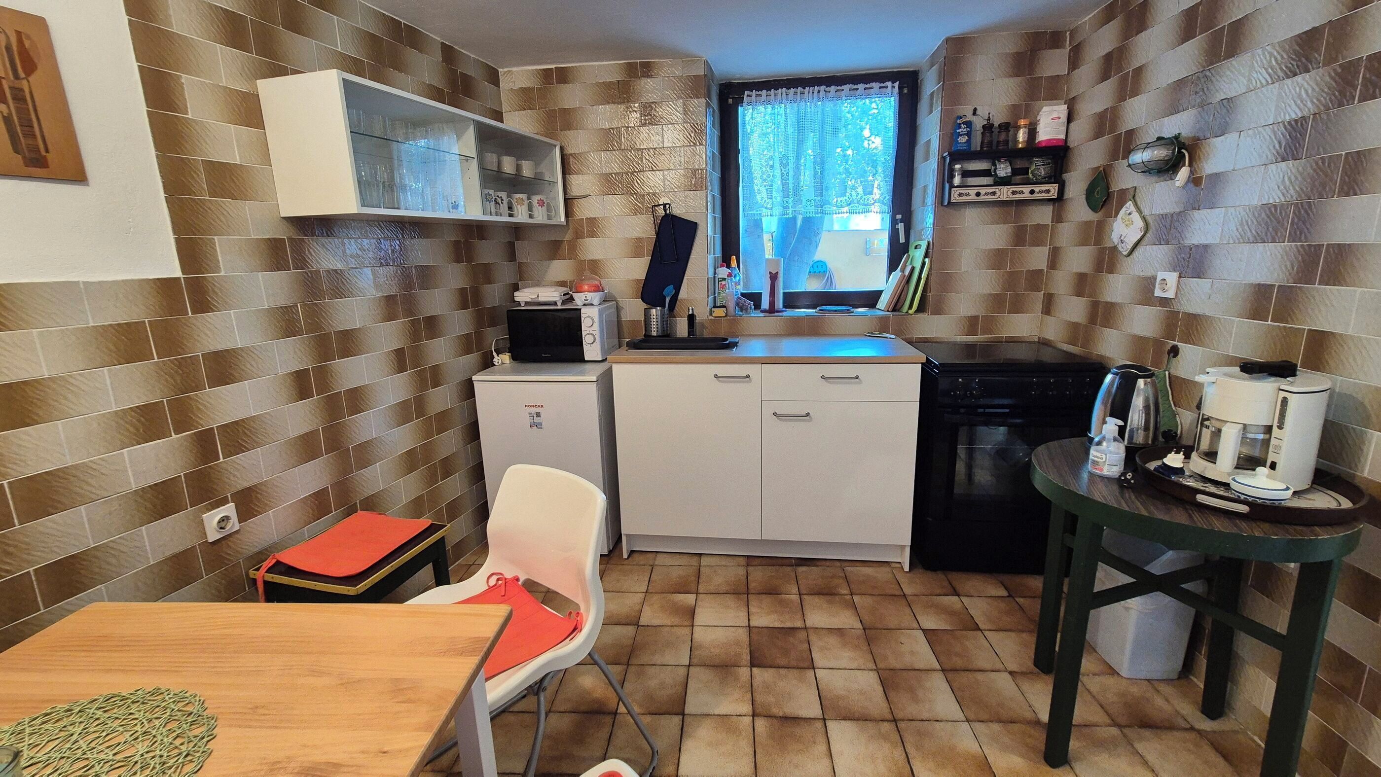 Una cocina compacta equipada con microondas, tostadora y cafetera. Cuenta con una pequeña zona de comedor con mesa y sillas.