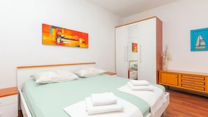 A neatly arranged bedroom with a bed, a wardrobe, and a painting on the wall. - Apartments Amulic (Duce)
