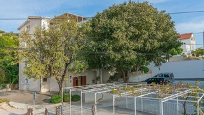 A residential area with a white building, a tree, and a parked car. - Apartments Amulic (Duce)